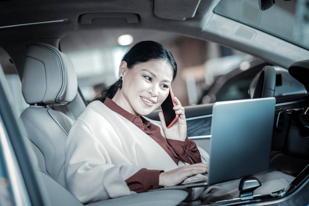 Pleasant smiling businesswoman calling her children on way home - Photo, image