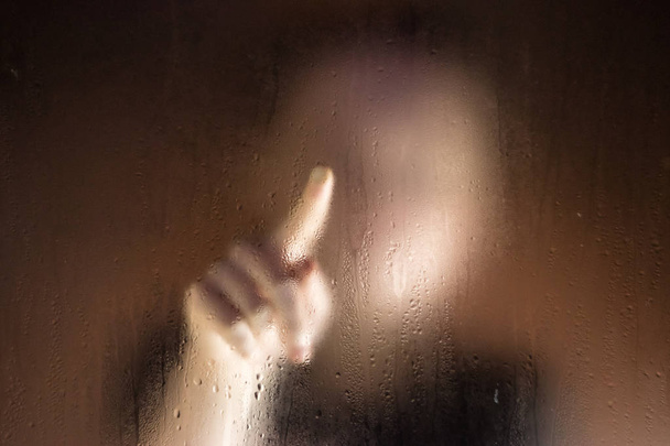 Girl outside window writes finger at wet glass. - Photo, Image