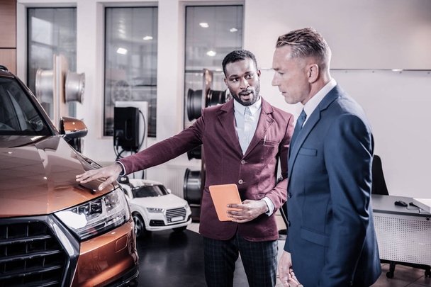 Sales manager wearing stylish jacket telling client about the car - Photo, Image