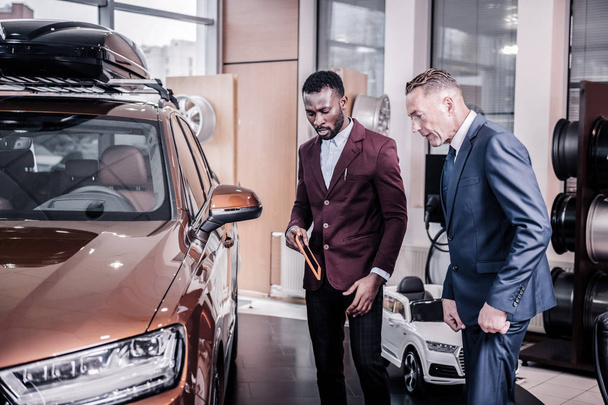 Businessmen standing in car showroom looking at hatchback car - Foto, Imagem
