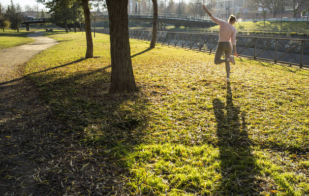 Nainen tekee venyttelyharjoituksia kaupunkipuistossa syksyllä. Hanki Shape in Your 30s käsite
 - Valokuva, kuva