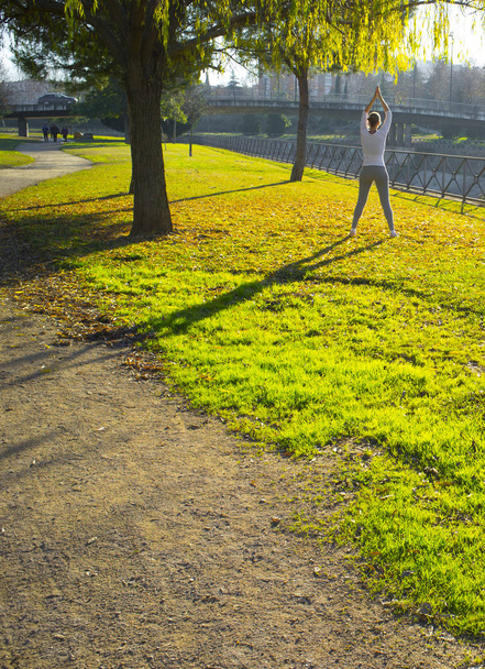 Woman doing stretching exercises at urban park in autumn season. Get in Shape in Your 30s concept - Photo, Image