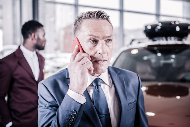 Handsome mature blue-eyed businessman speaking with wife by phone - Foto, imagen