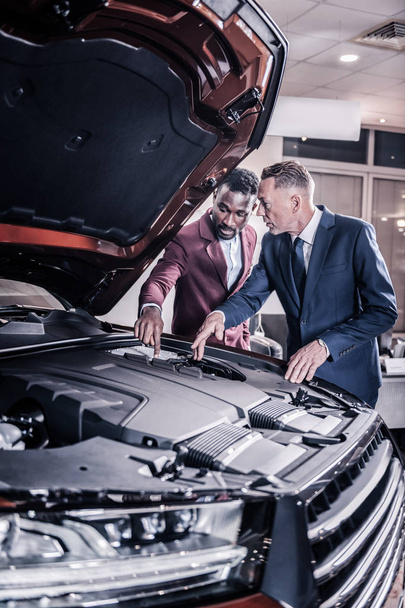 Sales manager opening front trunk telling about advantages of engine - Φωτογραφία, εικόνα