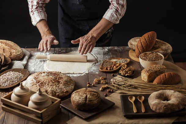 Man rolling out dough on kitchen table, close up - Valokuva, kuva