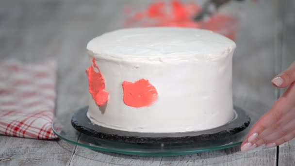 Pasticceria mano spalma crema rosa su torta di crema di spugna glassa bianca su giradischi in legno in cucina panificio, da vicino
. - Filmati, video