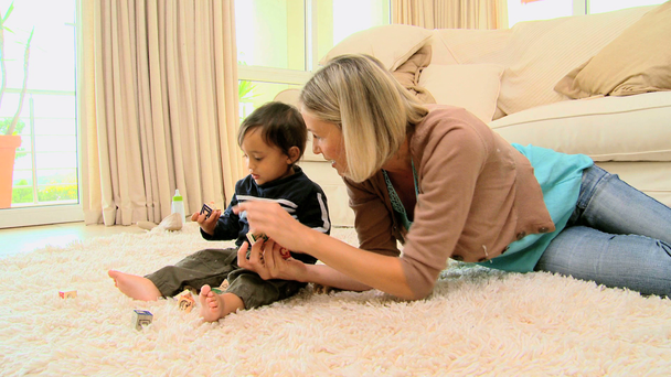 Young mother playing with baby on carpet - Footage, Video
