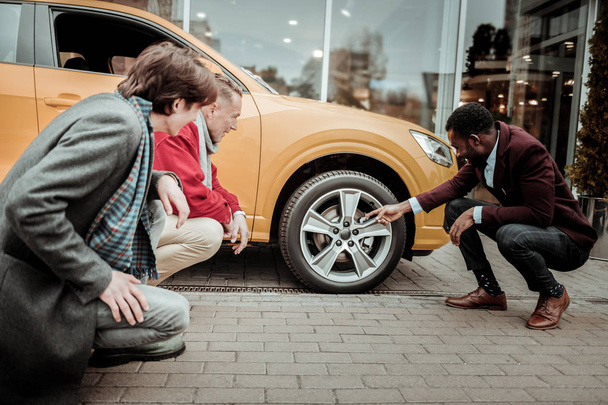 Sales manager wearing brown leather shoes telling about wheels - Foto, imagen