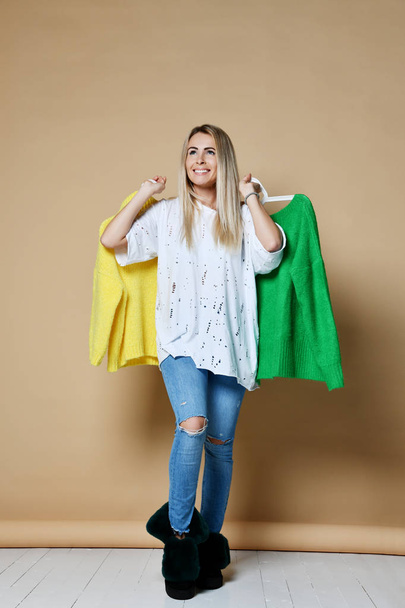 Woman shopping Christmas sale choose between two sweaters blouse green and yellow happy smiling  - Fotoğraf, Görsel