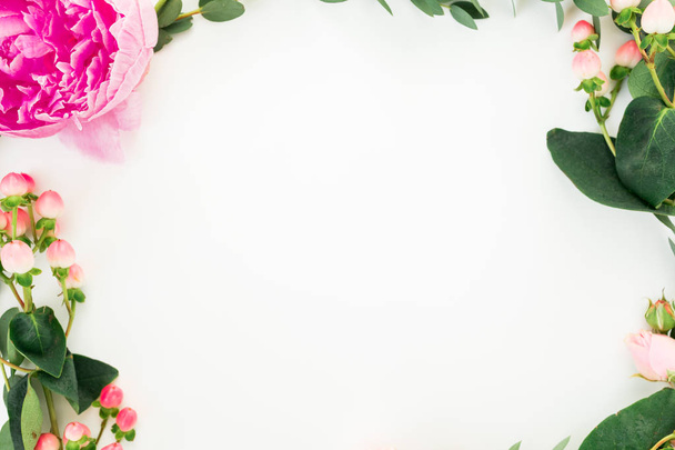 Floral frame of pink flowers and eucalyptus branches on white background. Flat lay, top view - Fotó, kép