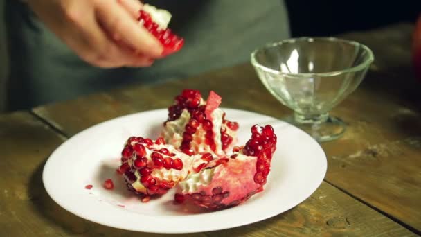 A woman separates the pomegranate grains into a glass vase. - Video