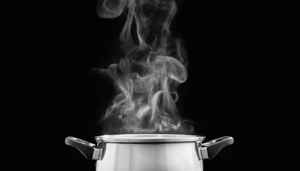 Dampf über Kochtopf in Küche auf dunklem Hintergrund - Foto, Bild