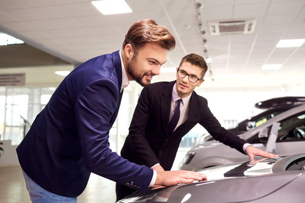 Car sale.Dealer and customer man buys a car in the showroom - Foto, imagen