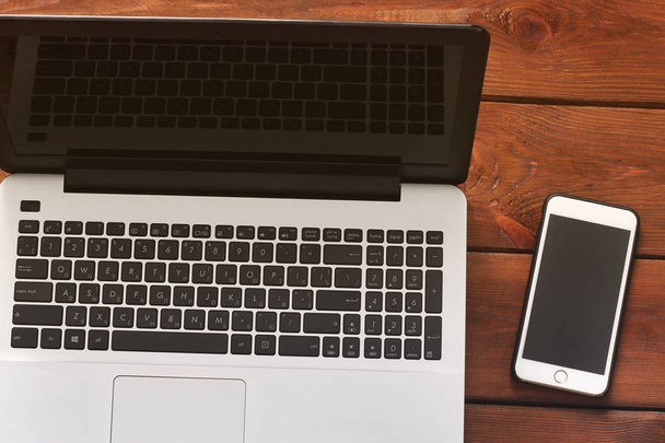 Laptop and phone on wooden background - Φωτογραφία, εικόνα