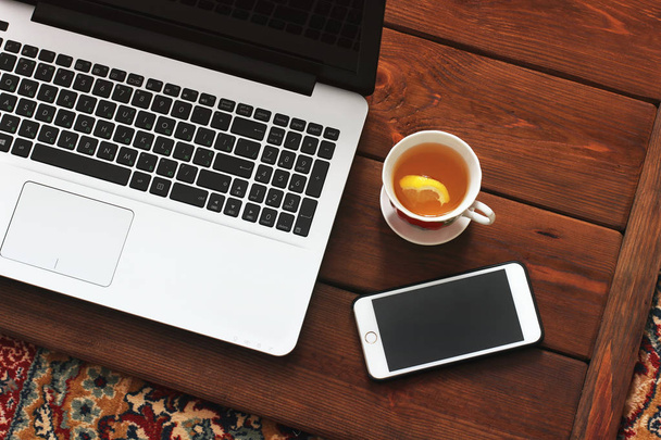 Laptop, phone and tea on wooden background - Photo, Image