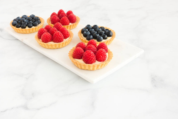 Homemade blueberry and raspberry and tarts on white marble board and background with copy space. - Photo, Image