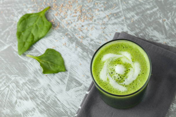 Fresh green spinach smoothie in a glass cup with yogurt on a gray wooden surface. Flat layout - Fotó, kép