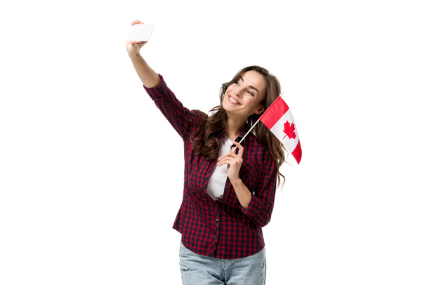 カナダの旗を保持していると白で隔離のスマート フォン selfie を撮影美しい女性 - 写真・画像