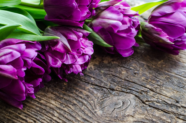 Flores de tulipán ultravioleta sobre una antigua mesa rústica de madera con lugar para el texto. Ramo de tulipanes de primavera púrpura. Feliz Día de la Madre. Tarjeta de felicitación del Día Internacional de la Mujer. Copiar espacio. Enfoque selectivo
. - Foto, Imagen