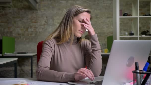 Closeup portret van moe uitgeput vrouwelijke beambte te typen op de laptop en een hoofdpijn hebben - Video