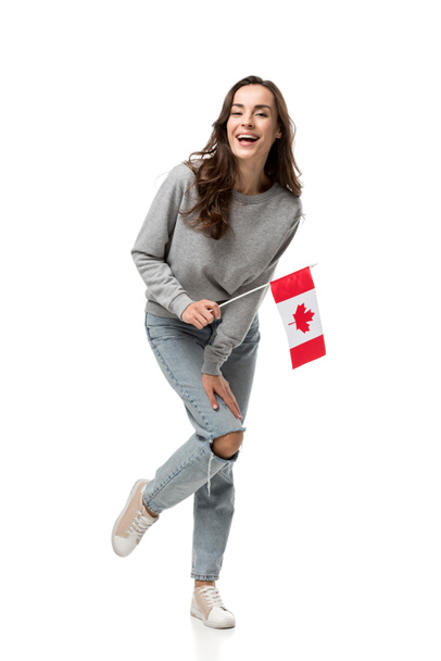 Kanada bayrağı tutarak ve üzerinde beyaz izole kamera bakarak gri rahat kıyafetler içinde heyecanlı kadın - Fotoğraf, Görsel