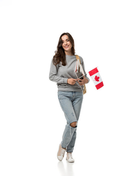 студентка, держащая канадский флаг и блокноты, глядя на камеру, изолированную на белом
 - Фото, изображение