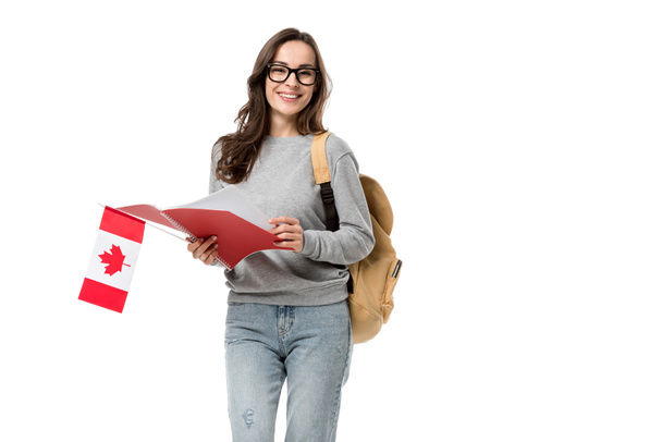 φοιτήτριας βλέπουν φωτογραφική μηχανή και κρατώντας καναδική σημαία με το σημειωματάριο που απομονώνονται σε λευκό - Φωτογραφία, εικόνα