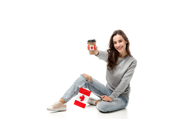 glückliche Frau mit kanadischer Flagge mit Kaffeebecher und Ahornblatt-Aufkleber isoliert auf weiß - Foto, Bild