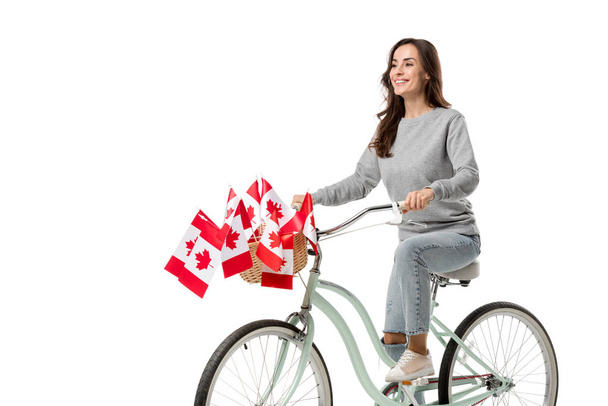 smiling woman riding vintage bicycle with canadian flags isolated on white - Valokuva, kuva