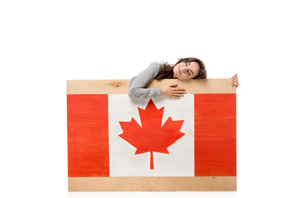woman with eyes closed holding wooden board with canadian flag isolated on white - Foto, Imagen
