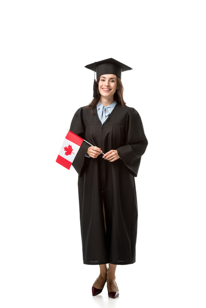 白で隔離カナダの国旗を保持している学術ガウンで美しい笑顔女子学生 - 写真・画像