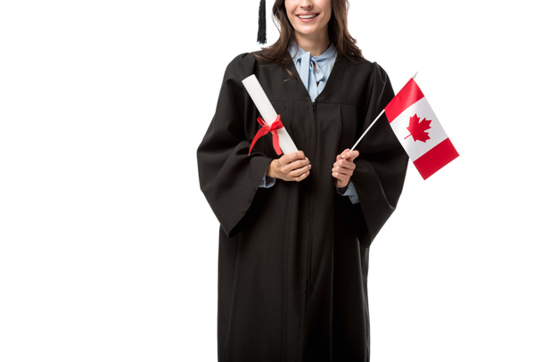 partial view of female student in academic gown holding canadian flag and diploma isolated on white - Photo, Image