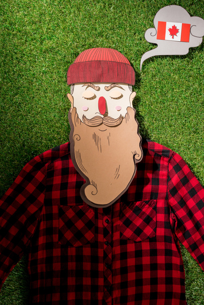 cardboard man in plaid shirt and thought bubble with canadian flag on green grass background - Φωτογραφία, εικόνα