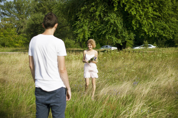 junges Liebespaar genießt die Natur, hält Händchen und geht mit Lavendel auf dem Feld spazieren. schöne Menschen in der Natur im Frühling bei Sonnenuntergang. - Foto, Bild