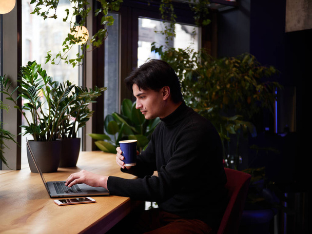 Homem de raça mista trabalhando com laptop e telefone inteligente no café
 - Foto, Imagem