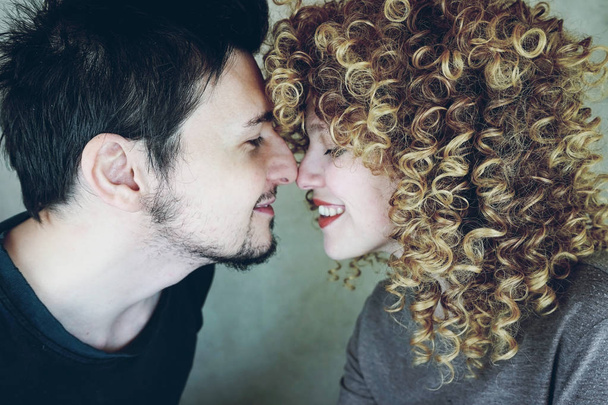 Portrait of a natural caucasian couple of young woman with curly blonde hair and man from side, they are happy and give affection each other - Photo, Image
