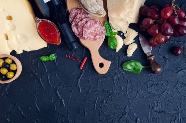 Bottle of wine, corkscrew and antipasti. Table full of mediterranean appetizers or antipasto. Assorted Italian style banquet party food set. Tradition wine tasting concept. Top view. Copy space. - Foto, imagen