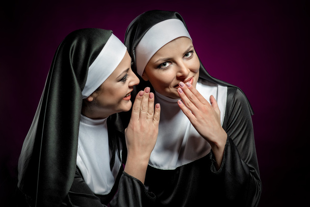 Young attractive nun whispering a secret to another nun - Фото, зображення