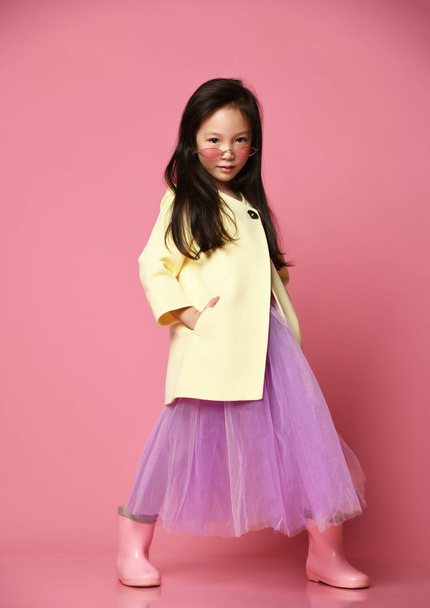 Little asian girl in yellow fashion jacket purple dress and modern red sunglasses posing - Photo, Image