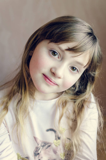 Porträt eines kleinen hübschen Mädchens mit süßem Lächeln. schönes Mädchen mit langen dunkelblonden Haaren und wunderbar ausdrucksstarken braunen Augen. Schulmädchen 8 Jahre alt. Nahaufnahme. verträumter optimistischer Blick. - Foto, Bild