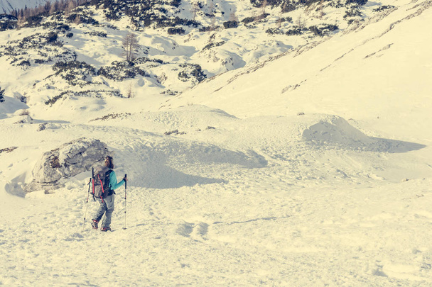 Alpinista hembra descendiendo al valle de montaña cruzando copos de nieve
. - Foto, Imagen