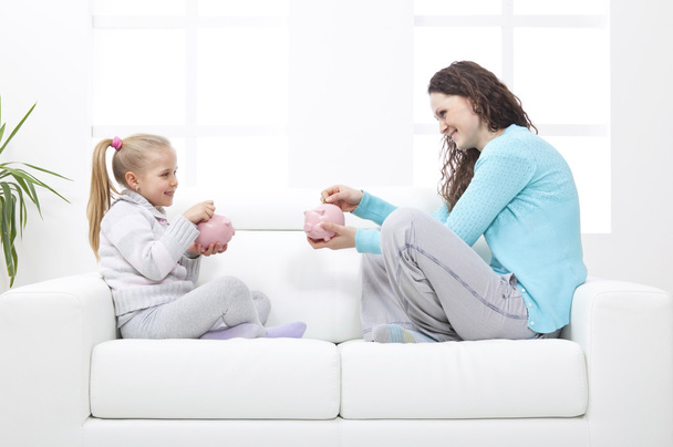 Madre e hija en el sofá aprenden sobre los ahorros
 - Foto, imagen