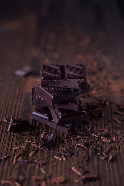 Column of dark or bitter or milk chocolate on a wood background - Foto, afbeelding