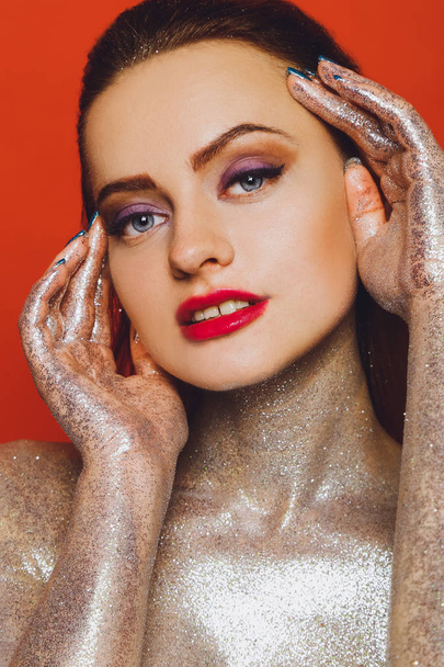 High fashion model girl in colorful bright spangles, glitter, in the studio on a red background, portrait of a beautiful sexy woman, fashionable glowing makeup. Colorful Brilliant Bright Makeup - Фото, зображення