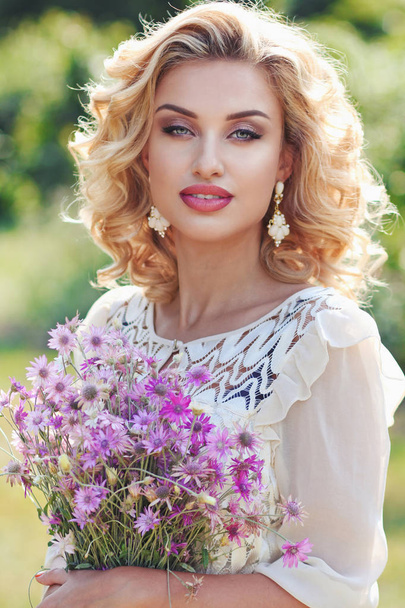Kręcone blond w parku z bukiet fiołek pole kwiat - Zdjęcie, obraz