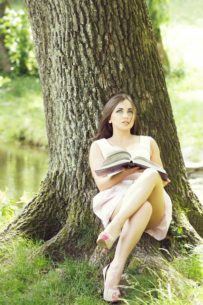 pretty woman reading book on grass - Photo, Image