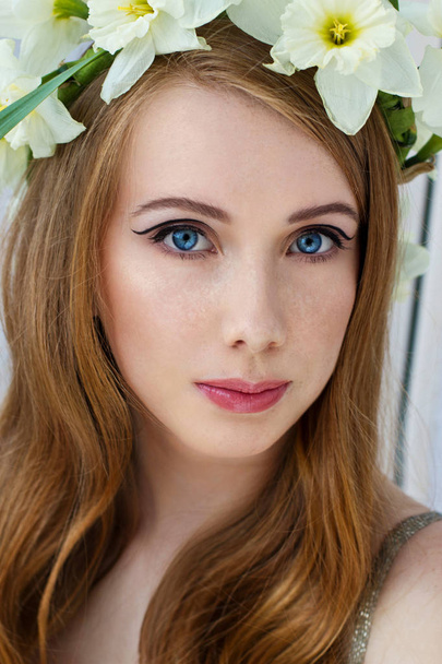 Portrait of a tender girl in a wreath of narcissus, spring freshness, light background - Valokuva, kuva