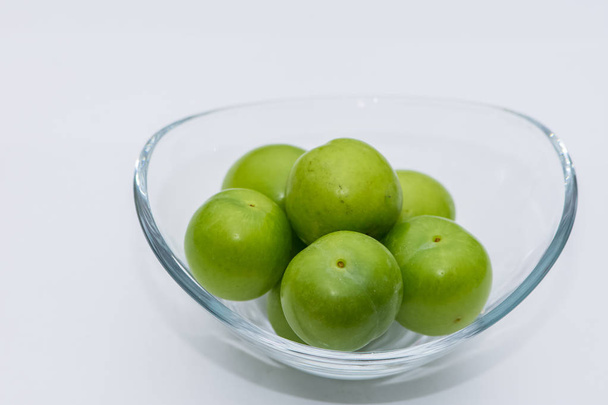 The small turkish green plums in the glass bowl in the studio - Photo, Image