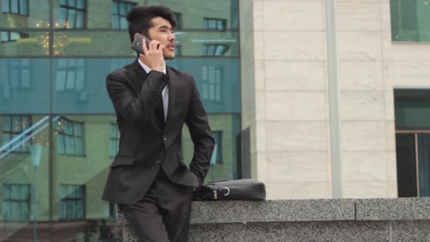 Hombre haciendo llamadas telefónicas frente a la oficina
 - Imágenes, Vídeo