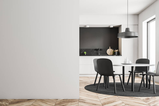 White round table with gray chairs standing in modern kitchen with white, black and black marble walls, wooden floor and white countertops. Mock up wall on the left. 3d rendering - Φωτογραφία, εικόνα
